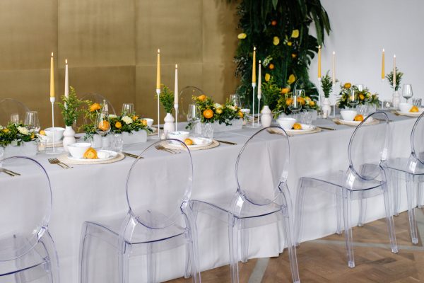 Frühlingsdekoration für ein Event mit Ghost Style Stühlen, Goldbesteck, weißer Tischdecke und Platzsets